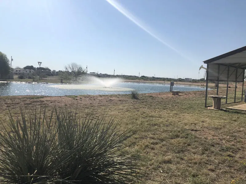 Fenced fishing pond with lit fountain and walking path
